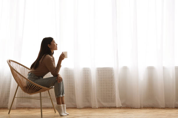 Girl Sitting In Modern Chair, Enjoying Morning Coffee Calm Morning. Girl Sitting In Modern Chair, Enjoying Coffee In Front Of Window, Side View coffee drink stock pictures, royalty-free photos & images