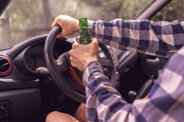 istock young crazy drunk man driving the car and drinking alcohol 1159989762