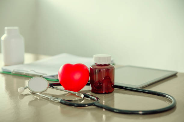 istock Red heart shape placed with medic bottle and stethoscope on doctor table. 1159990728