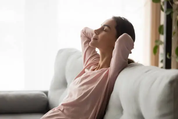 Photo of Side view serene woman leaning on couch dreaming at home