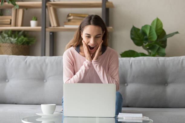 istock Woman sitting on couch reading received email feels surprised amazed 1159994009