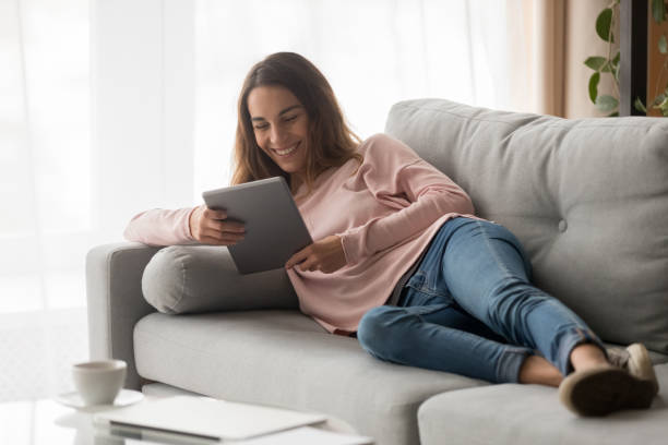istock Woman lying on couch with tablet spending time at home 1159994011