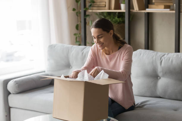 mulher do cliente que senta-se na caixa da caixa do unbox do sofá satisfeito - package box gift delivering - fotografias e filmes do acervo