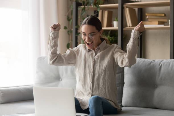 istock Excited woman looking at computer screen celebrating online win 1159994564