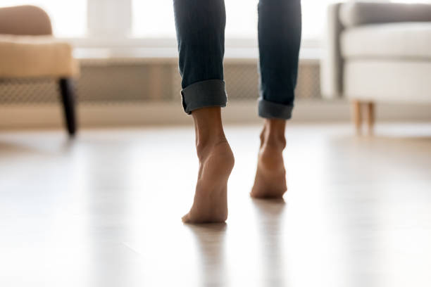 Rear view woman feet heel close up stands on tiptoes Rear view close up cropped image caucasian barefoot woman feet in blue jeans, female stands on tiptoes enjoys modern home warm electric underfloor heating or active girl moving dancing indoors concept tiptoe stock pictures, royalty-free photos & images