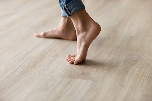 Vista lateral de la mujer vista de los pies se encuentra en el suelo de madera caliente photo