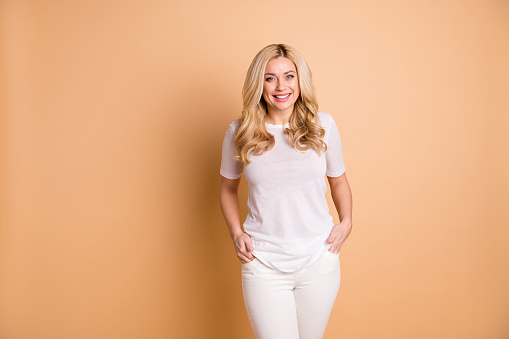 Close up photo amazing beautiful she her lady hands arms pockets, nice toothy smile kindhearted easy-going person sincere wear casual pants trousers white t-shirt isolated beige pastel background