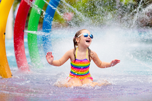 Kids play in aqua park. Children at water playground of tropical amusement park. Little girl at swimming pool. Child playing at water slide on summer vacation in Asia. Swim wear for young kid.