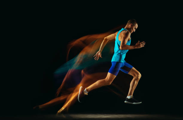 istock Professional male runner training isolated on black studio background in mixed light 1159995337