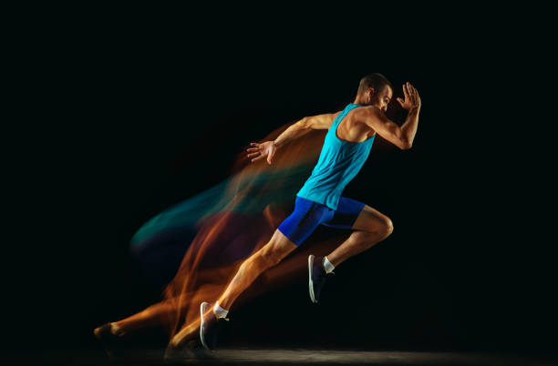 istock Professional male runner training isolated on black studio background in mixed light 1159995356