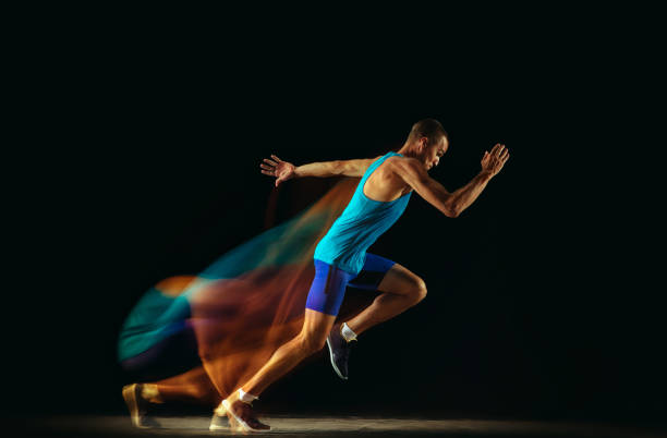 istock Professional male runner training isolated on black studio background in mixed light 1159995357