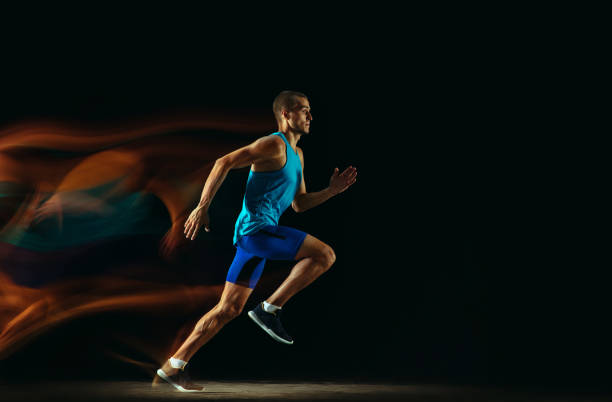 istock Professional male runner training isolated on black studio background in mixed light 1159995358