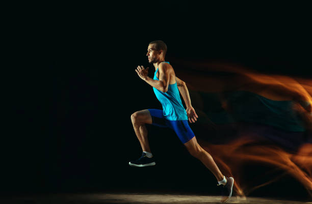 istock Professional male runner training isolated on black studio background in mixed light 1159995359