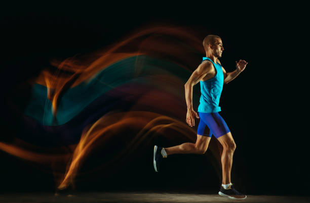 istock Professional male runner training isolated on black studio background in mixed light 1159995361