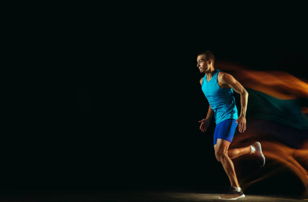 istock Professional male runner training isolated on black studio background in mixed light 1159995364