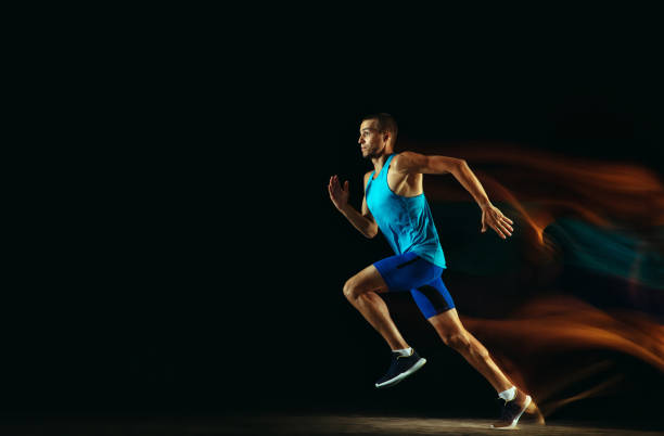 istock Professional male runner training isolated on black studio background in mixed light 1159995366