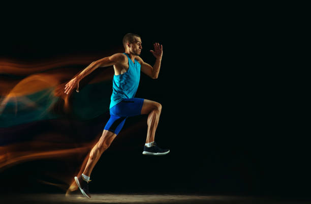 istock Professional male runner training isolated on black studio background in mixed light 1159995369
