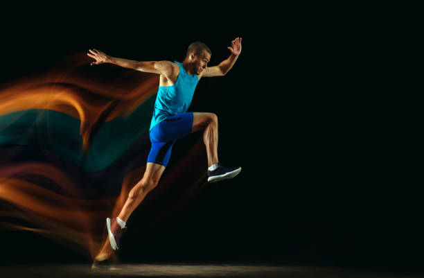 istock Professional male runner training isolated on black studio background in mixed light 1159995371