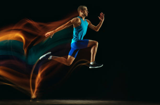 istock Professional male runner training isolated on black studio background in mixed light 1159995377