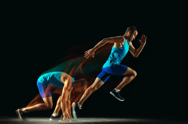 istock Professional male runner training isolated on black studio background in mixed light 1159995379