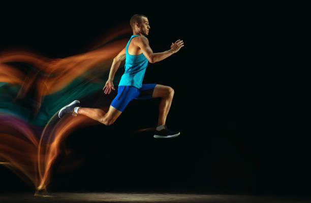 istock Professional male runner training isolated on black studio background in mixed light 1159995390