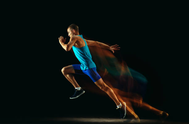 istock Professional male runner training isolated on black studio background in mixed light 1159995423