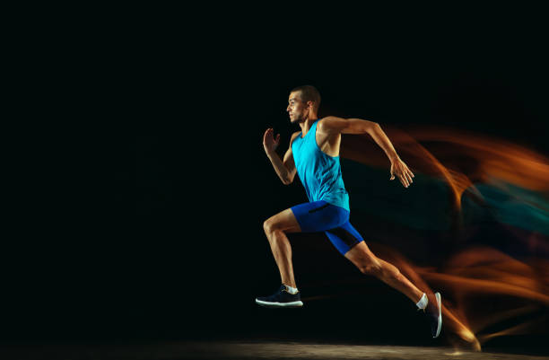 istock Professional male runner training isolated on black studio background in mixed light 1159995988