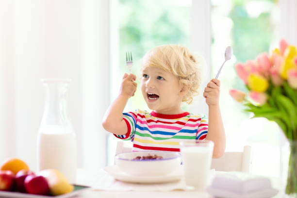 istock Child eating breakfast. Kid with milk and cereal. 1159997619