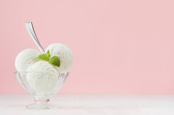 istock Vanilla ice cream scoops in elegant bowl with green mint, silver spoon in modern stylish pastel pink interior. 1159997668