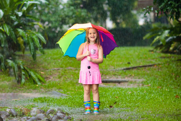 gosse avec le parapluie jouant sous la pluie d'été. - 18602 photos et images de collection