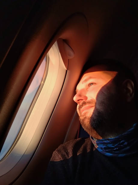 istock Pensive man looks out through the porthole of an airplane 1160000278