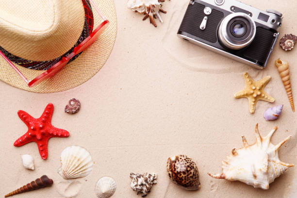 istock Beach accessories - sunglasses, hat and camera on sand witn shells and seastar. 1160000824
