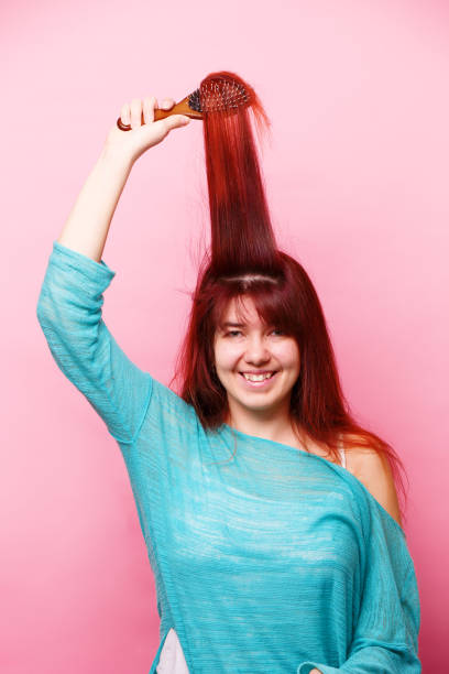 istock Woman brushing her hair on pink background 1160001986