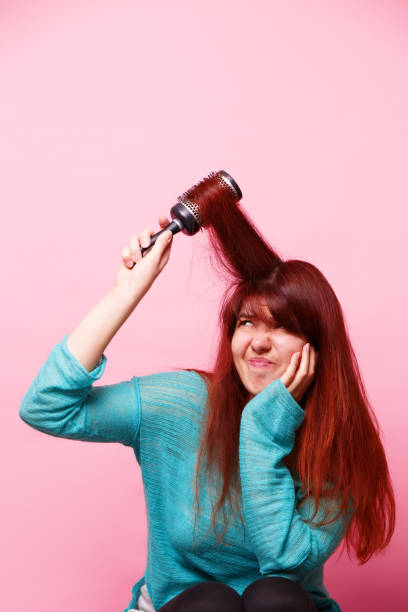 istock Woman brushing her hair on pink background 1160002097