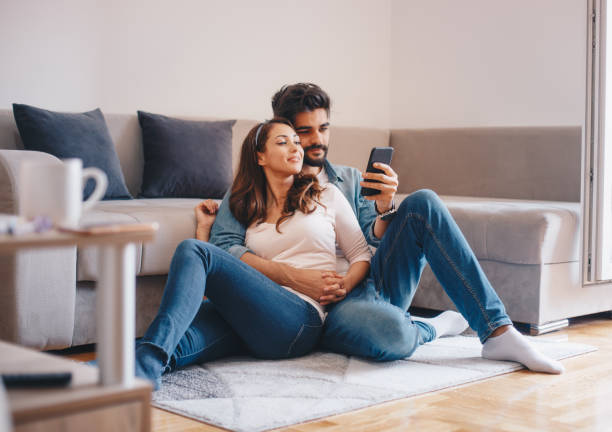 Couple looking at mobile phone at home stock photo
