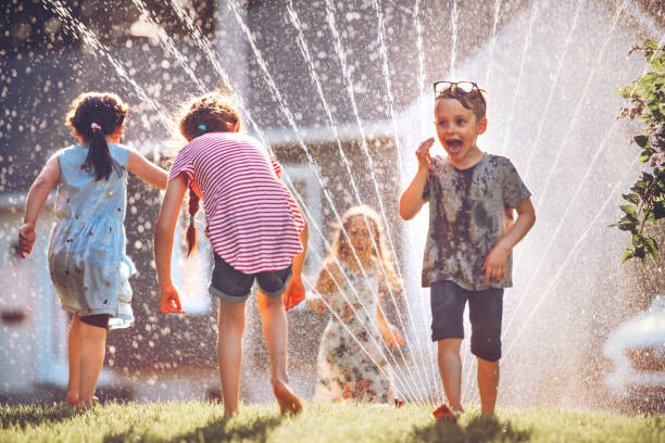 istock Happy kids playing with garden sprinkler 1160005152