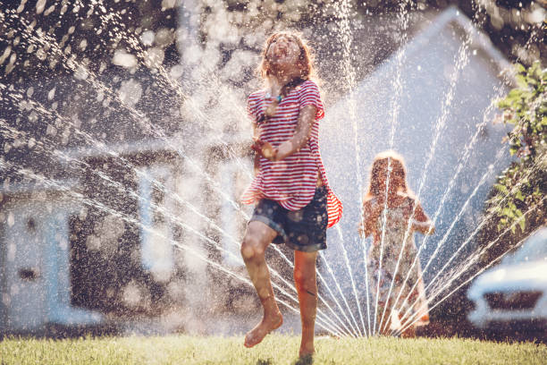 istock Happy kids playing with garden sprinkler 1160005155