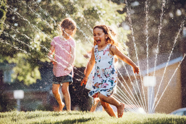 istock Happy kids playing with garden sprinkler 1160005167