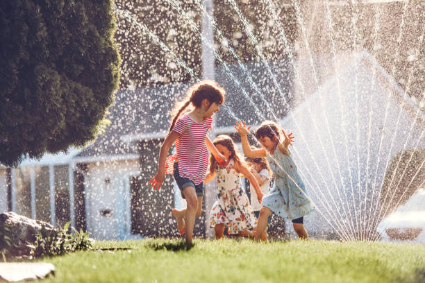 istock Happy kids playing with garden sprinkler 1160005302