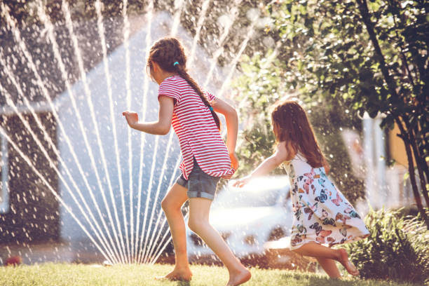 istock Happy kids playing with garden sprinkler 1160005308