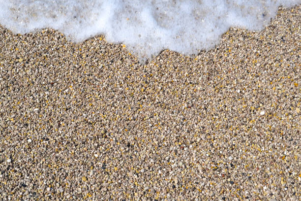istock Sea foamy wave on a pebble beach top view 1160006417