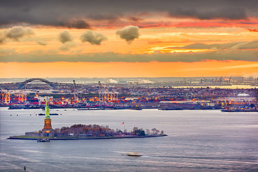 New York Harbor, New York, USA with the Statue of Liberty and Bayonne, New Jersey in the background.