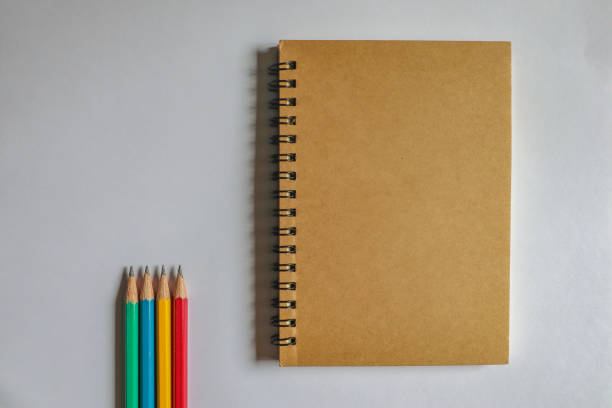 istock Multi-colored pencils and brown notebooks on a white background can be used to make backgrounds. 1160007644