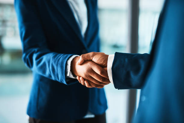 Partner up and pursue your goals together Cropped shot of two businesspeople shaking hands in a modern office global business handshake stock pictures, royalty-free photos & images