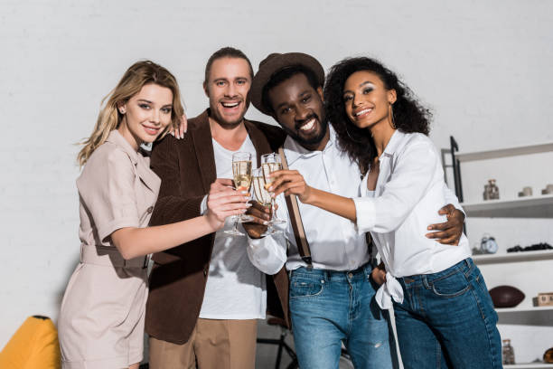 istock low angle view of cheerful multicultural friends smiling while clinking champagne glasses 1160010244