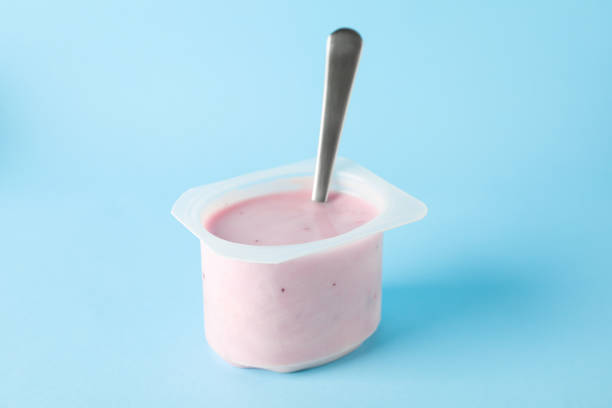 istock Plastic cup with yogurt and spoon on color background, space for text 1160010820