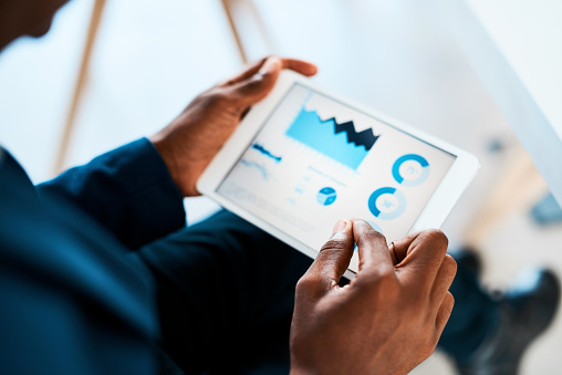 Cropped shot of a businesswoman using a digital tablet with graphs on it in a modern office