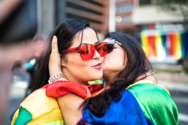Lesbian couple kissing during the LGBTQI parade Lesbian couple kissing during the LGBTQI parade gay long hair stock pictures, royalty-free photos & images