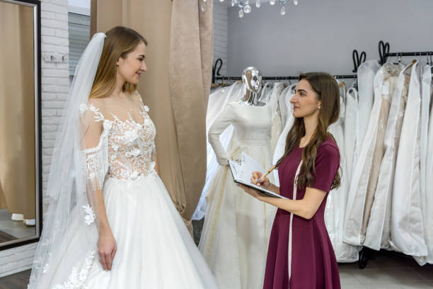 istock Dressmaker with notepad in wedding salon and bride 1160013479