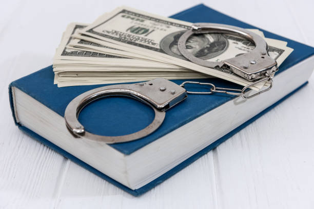 istock Dollar banknotes with handcuffs on blue book 1160015176